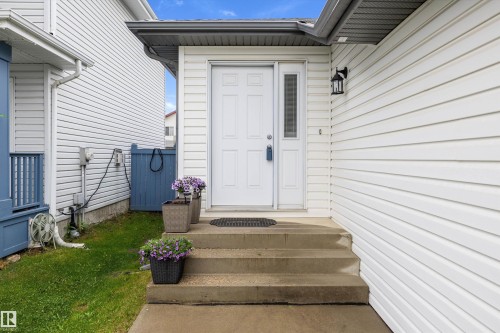 White paneled siding exterior featuring a white paneled entry door with an adjacent vertical window pane - 3344 24 Avenue Nw, Edmonton, AB - Outdoor With Exterior