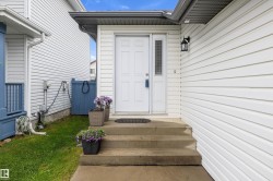 White paneled siding exterior featuring a white paneled entry door with an adjacent vertical window pane - 