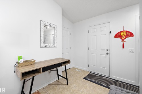 White paneled door with brushed nickel hardware, light-toned tile flooring, and white baseboards - 3344 24 Avenue Nw, Edmonton, AB - Indoor