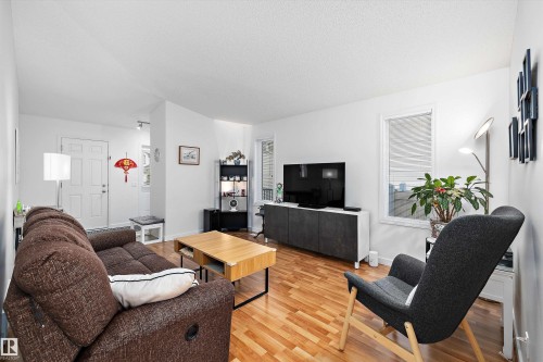 Bright living area featuring wood-finish flooring, white walls, and a white entry door - 3344 24 Avenue Nw, Edmonton, AB - Indoor Photo Showing Living Room