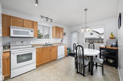 Kitchen featuring wood cabinetry, white appliances, a double basin sink, and a tiled floor - 