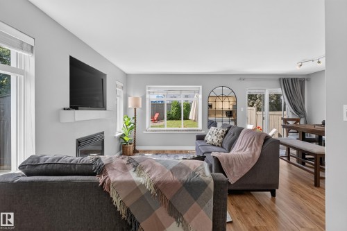Living area featuring a built-in fireplace, wood-finish flooring, recessed lighting, and sliding glass doors - #25 200 Erin Ridge Dr, St. Albert, AB - Indoor Photo Showing Other Room With Fireplace