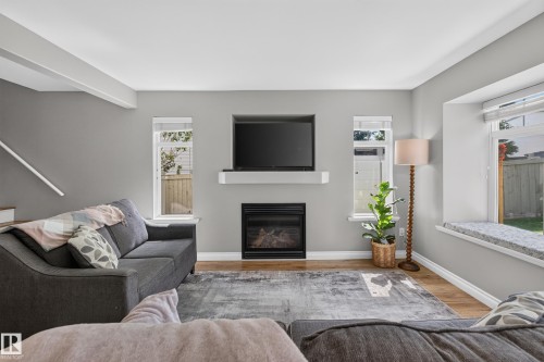 Wood-finish flooring, built-in fireplace, white mantel, multiple windows, and a window seat - #25 200 Erin Ridge Dr, St. Albert, AB - Indoor Photo Showing Living Room With Fireplace