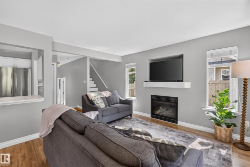 Built-in fireplace with a white floating mantel, recessed television alcove, and wood-finish flooring - #25 200 Erin Ridge Dr, St. Albert, AB - Indoor Photo Showing Living Room With Fireplace