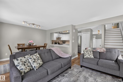 Open-concept living area featuring two gray upholstered sofas with geometric accent pillows, hardwood flooring, and recessed lighting - #25 200 Erin Ridge Dr, St. Albert, AB - Indoor Photo Showing Living Room