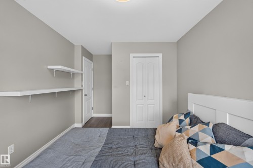 Bright secondary bedroom featuring neutral gray walls, white six-panel door, and white painted wood bed frame - #25 200 Erin Ridge Dr, St. Albert, AB - Indoor Photo Showing Bedroom