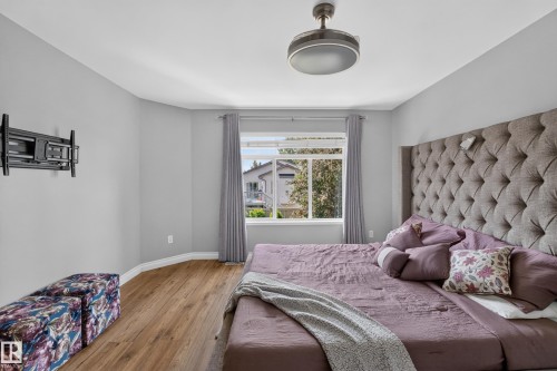 Wood-finish flooring, a ceiling fan with integrated lighting, and a wall-mounted television bracket - #25 200 Erin Ridge Dr, St. Albert, AB - Indoor Photo Showing Bedroom