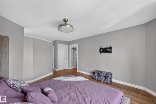 Wood-finish flooring, recessed lighting, crown molding, and a built-in wall mount - #25 200 Erin Ridge Dr, St. Albert, AB - Indoor Photo Showing Bedroom