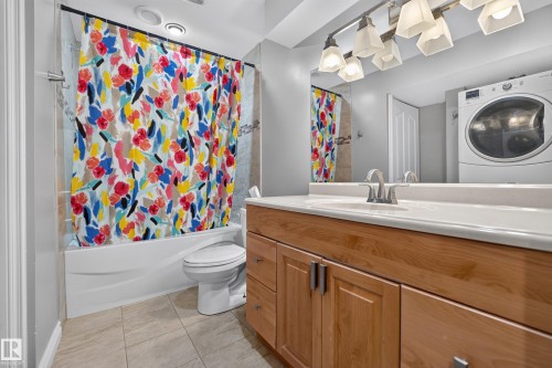 Spa-inspired bathroom featuring a wood-finish vanity with dual sinks, white quartz countertop, and brushed nickel fixtures - #25 200 Erin Ridge Dr, St. Albert, AB - Indoor