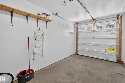 Spacious garage with finished walls, concrete flooring, wooden beam framing, and an overhead sectional garage door - #25 200 Erin Ridge Dr, St. Albert, AB - Indoor Photo Showing Garage