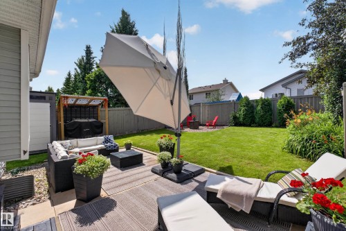 Expansive backyard oasis featuring a manicured lawn, mature landscape plantings, and composite decking - #25 200 Erin Ridge Dr, St. Albert, AB - Outdoor