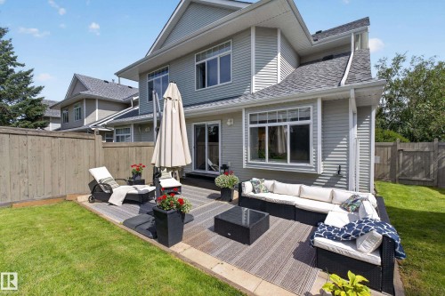 Private backyard with a multi-level wood-finish deck, surrounded by a wood fence, and featuring a manicured lawn - #25 200 Erin Ridge Dr, St. Albert, AB - Outdoor