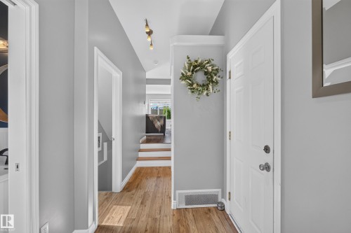 Bright hallway featuring pristine white six-panel doors, warm wood-finish flooring, soft gray walls, and recessed lighting throughout - #25 200 Erin Ridge Dr, St. Albert, AB - Indoor Photo Showing Other Room