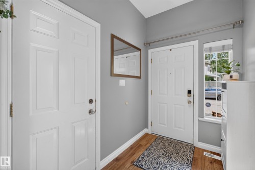 Welcoming foyer showcasing hardwood flooring, soft gray walls, and multiple white six-panel doors with brushed nickel hardware - #25 200 Erin Ridge Dr, St. Albert, AB - Indoor Photo Showing Other Room