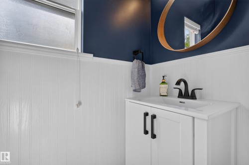 White beadboard wainscoting, a modern vanity with a single basin sink, matte black faucet, and coordinating hardware - #25 200 Erin Ridge Dr, St. Albert, AB - Indoor Photo Showing Bathroom