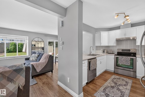 Contemporary kitchen with white cabinetry, stainless steel appliances, and tile backsplash - #25 200 Erin Ridge Dr, St. Albert, AB - Indoor Photo Showing Kitchen