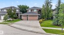 Two-story residence featuring a two-car garage with wood-finish doors, a stone facade accent, an arched entryway, and a landscaped front yard with mature trees - 2489 Martell Crescent Nw, Edmonton, AB  - Outdoor 