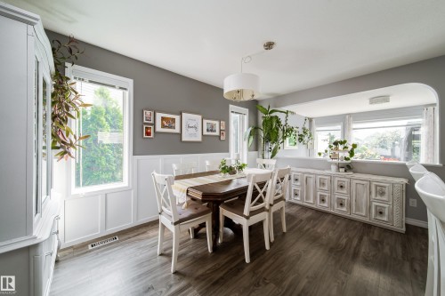 Bright dining area featuring hardwood-finish flooring, a round wood table with X-back chairs, and abundant natural light from multi-pane windows - 7239 21 Avenue Sw, Edmonton, AB - Indoor Photo Showing Dining Room