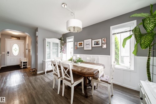 Bright dining area showcasing hardwood flooring, a wood dining table with X-back chairs, and abundant natural light from multi-pane windows - 7239 21 Avenue Sw, Edmonton, AB - Indoor Photo Showing Dining Room