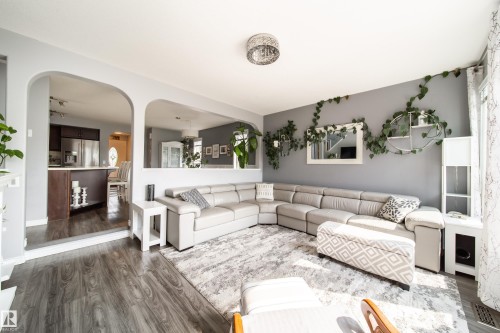 Spacious open-concept living area featuring a sectional layout with wood-finish flooring, recessed ceiling lighting, and abundant natural light - 7239 21 Avenue Sw, Edmonton, AB - Indoor Photo Showing Living Room