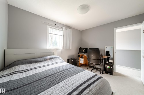Bright secondary bedroom featuring neutral gray walls, a large window with natural light, light-finish flooring, and a white panel door - 7239 21 Avenue Sw, Edmonton, AB - Indoor Photo Showing Bedroom