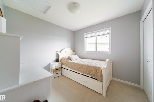 Bright secondary bedroom featuring neutral gray walls, wood-finish flooring, and abundant natural light from a multi-pane window - 7239 21 Avenue Sw, Edmonton, AB - Indoor Photo Showing Bedroom