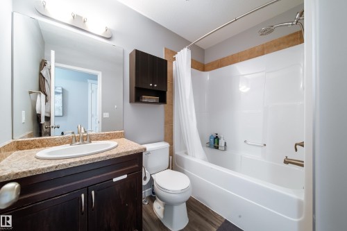 Bathroom featuring a single vanity with an oval sink, solid surface countertop, and wood-finish cabinetry - 7239 21 Avenue Sw, Edmonton, AB - Indoor Photo Showing Bathroom