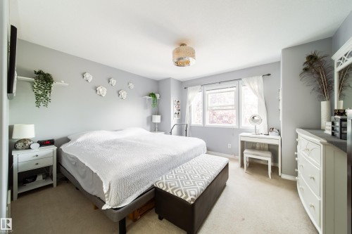 Carpeted bedroom featuring light gray walls, a multi-pane window, and a decorative ceiling light fixture - 7239 21 Avenue Sw, Edmonton, AB - Indoor Photo Showing Bedroom