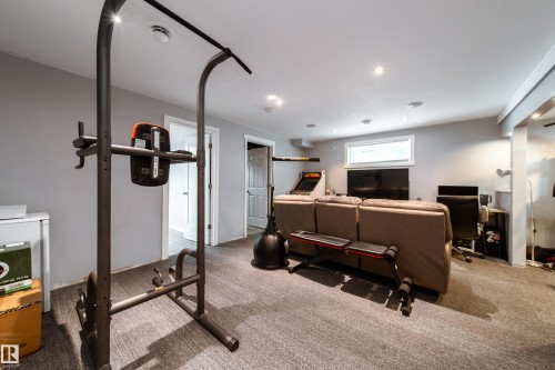 Finished basement recreation space featuring neutral carpeting, recessed ceiling lighting, and dedicated fitness area with pull-up bar station - 7239 21 Avenue Sw, Edmonton, AB - Indoor Photo Showing Gym Room