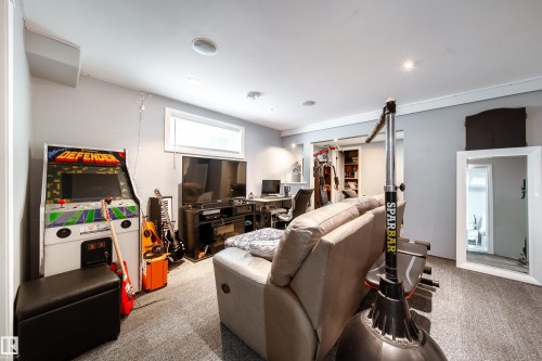Finished basement recreation room featuring recessed ceiling lighting, neutral carpeting, and built-in cabinetry - 7239 21 Avenue Sw, Edmonton, AB - Indoor