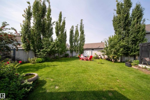 Expansive backyard with a manicured lawn, established perimeter fencing, and mature trees - 7239 21 Avenue Sw, Edmonton, AB - Outdoor With Backyard