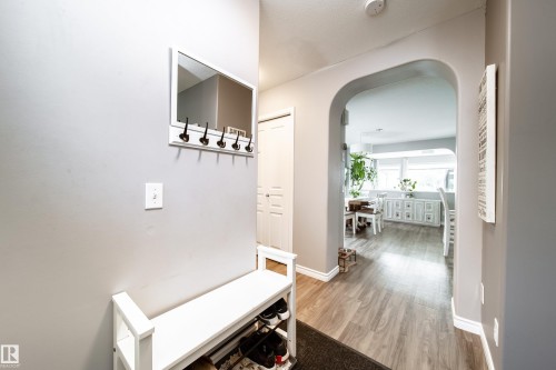Archway entry into an open-concept space featuring wood-finish flooring and a built-in white cabinet with multiple drawers - 7239 21 Avenue Sw, Edmonton, AB - Indoor