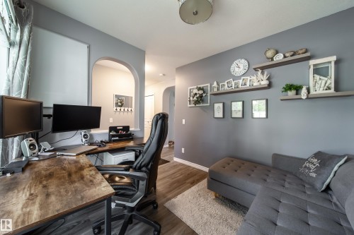 Wood-finish flooring throughout, complemented by a gray accent wall - 7239 21 Avenue Sw, Edmonton, AB - Indoor Photo Showing Office