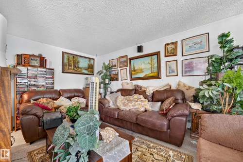 Living area with wall-mounted artwork, textured ceiling, and neutral wall color - #206 10842 107 St Nw, Edmonton, AB - Indoor Photo Showing Living Room