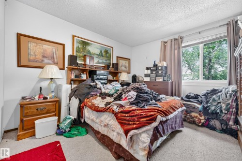 Bedroom featuring a window with exterior tree views, wall-to-wall carpeting, and white painted walls - #206 10842 107 St Nw, Edmonton, AB - Indoor Photo Showing Bedroom