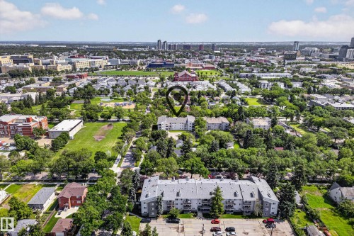 Aerial perspective showcasing a residential neighborhood with extensive green spaces and mature tree canopies - #206 10842 107 St Nw, Edmonton, AB - Outdoor With View