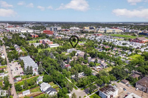 Aerial view showcasing a tree-lined residential neighborhood with mature landscaping, single-family homes, and abundant green space throughout the community - #206 10842 107 St Nw, Edmonton, AB - Outdoor With View