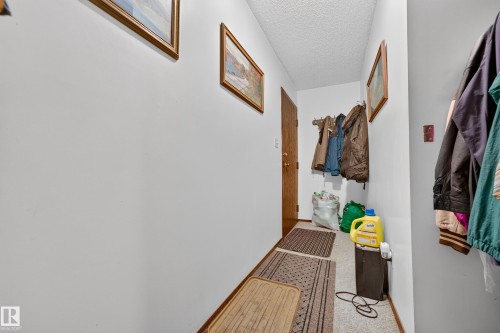 Entryway featuring a wood-panel door, coat hooks, and light-colored walls - #206 10842 107 St Nw, Edmonton, AB - Indoor Photo Showing Other Room