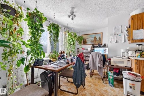 Functional room featuring a window, textured ceiling, patterned floor, and wood-finish cabinetry - #206 10842 107 St Nw, Edmonton, AB - Indoor
