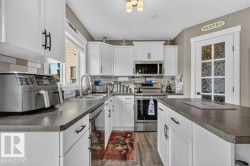 Kitchen featuring white shaker-style cabinetry, dark countertops, and stainless steel appliances - 