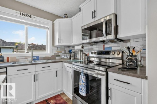 White shaker cabinetry with matte black hardware, stainless steel appliances, and a mosaic tile backsplash - 5322 Terwillegar Boulevard Nw, Edmonton, AB - Indoor Photo Showing Kitchen With Double Sink