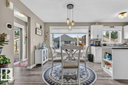 Open-concept dining area featuring wood-finish flooring, a contemporary triple pendant light fixture, and a large window providing natural illumination - 