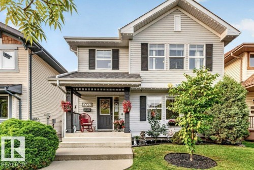 Two-story residence featuring light-colored horizontal siding, a covered front porch with dark columns, and a gabled roofline - 5322 Terwillegar Boulevard Nw, Edmonton, AB - Outdoor
