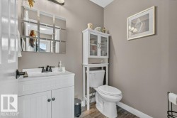Bathroom featuring a white vanity with paneling and dark hardware, black faucet, and a wall-mounted mirror - 