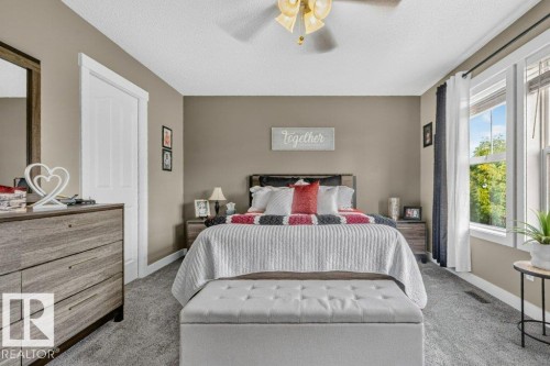 Wall-to-wall carpeting, multiple windows providing natural light, a ceiling fan with integrated lighting, and a white paneled door with matching trim - 5322 Terwillegar Boulevard Nw, Edmonton, AB - Indoor Photo Showing Bedroom