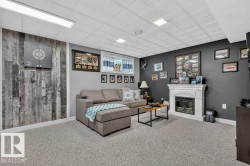 Spacious room featuring gray carpet flooring and a multi-toned wood plank accent wall - 