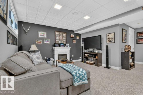 Finished lower level featuring recessed lighting, a decorative fireplace surround, neutral wall paint, and light-colored carpeting - 5322 Terwillegar Boulevard Nw, Edmonton, AB - Indoor With Fireplace