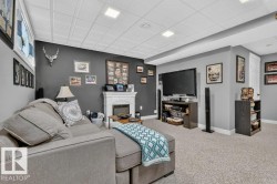 Finished lower level featuring recessed lighting, a decorative fireplace surround, neutral wall paint, and light-colored carpeting - 