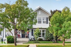 Gabled two-story home featuring light grey siding and dark shutters - 