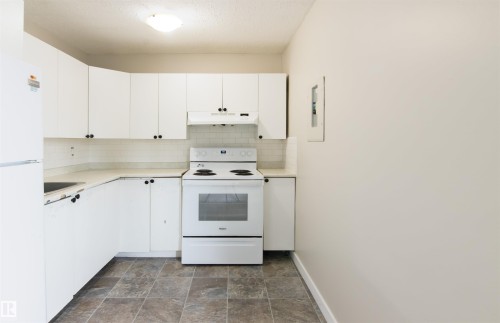 Kitchen with white appliances, light countertops, white cabinetry, stone finish floors, and a textured ceiling - 11029 95 Street Nw, Edmonton, AB - Indoor Photo Showing Kitchen